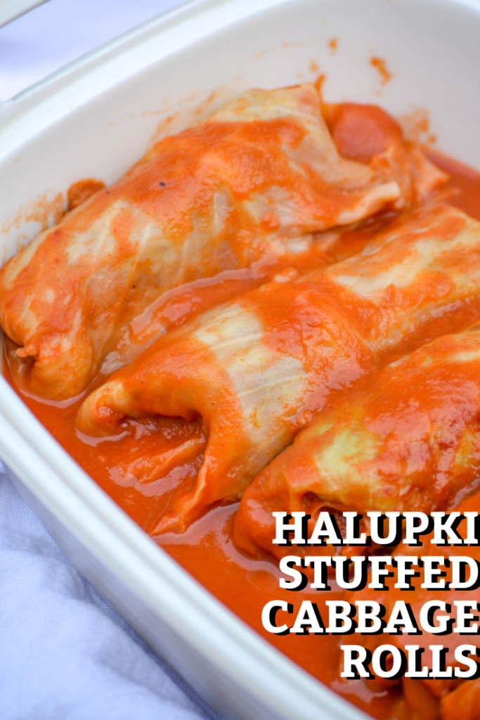 halupki stuffed cabbage rolls shown bathed in sauce in a deep casserole dish with the title of the dish overlayed in bold type