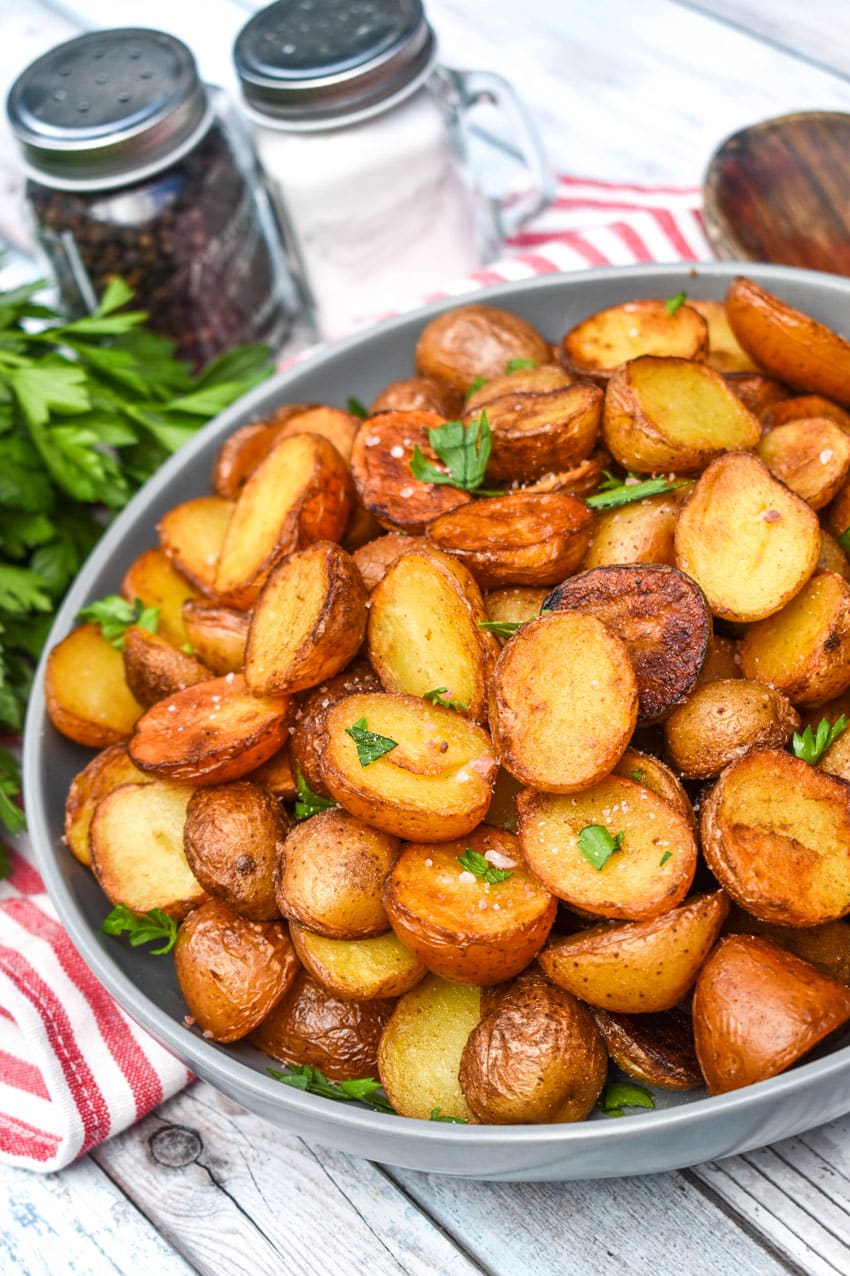 crispy salt and vinegar potatoes topped with fresh herbs in a shallow gray bowl