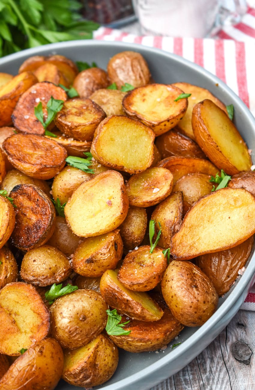 crispy salt and vinegar potatoes topped with fresh herbs in a shallow gray bowl