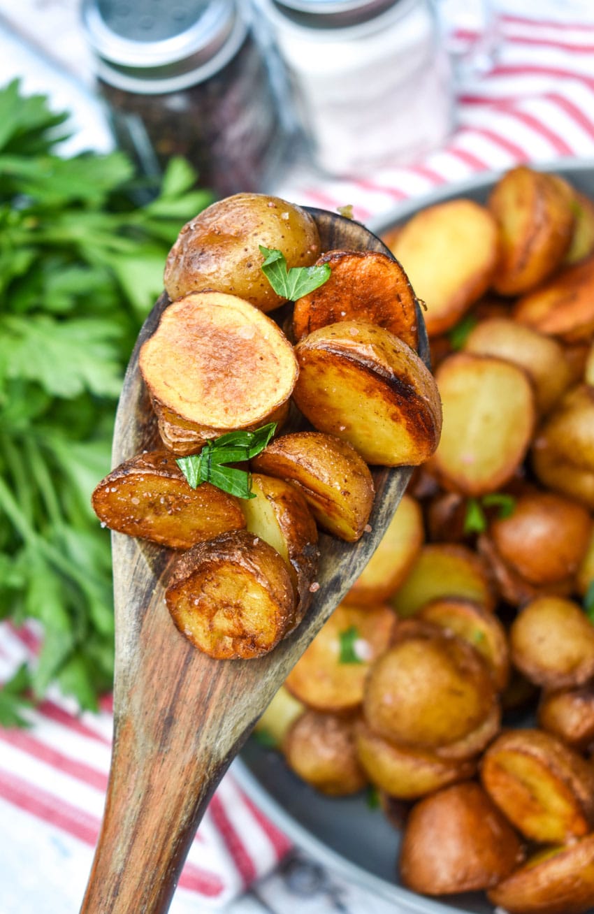 a wooden spoon holding up a scoop of salt and vinegar potatoes