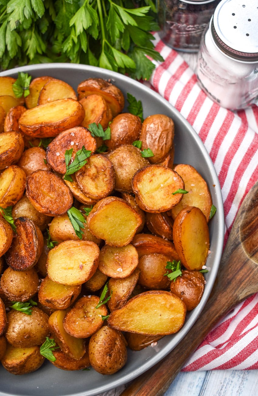 crispy salt and vinegar potatoes topped with fresh herbs in a shallow gray bowl