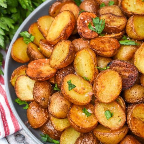 crispy salt and vinegar potatoes topped with fresh herbs in a shallow gray bowl