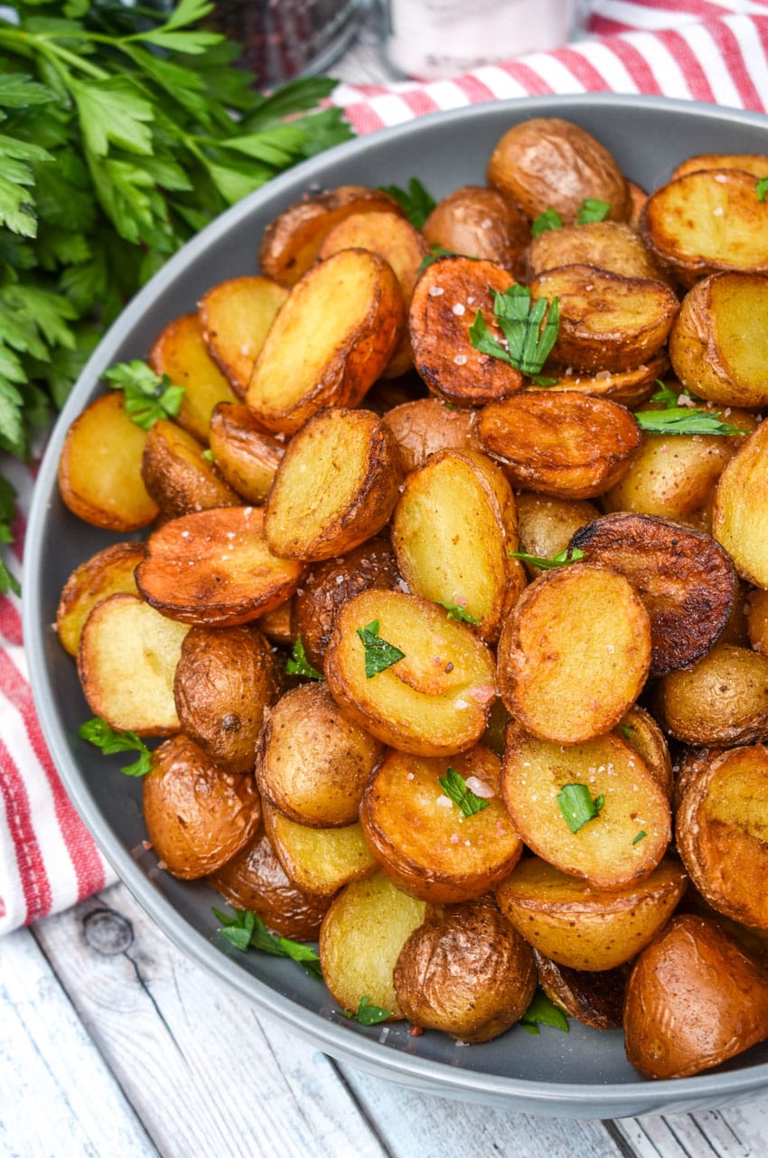 crispy salt and vinegar potatoes topped with fresh herbs in a shallow gray bowl