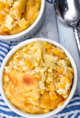 Southern creamed corn pudding in two small white ramekins with a silver spoon on the side