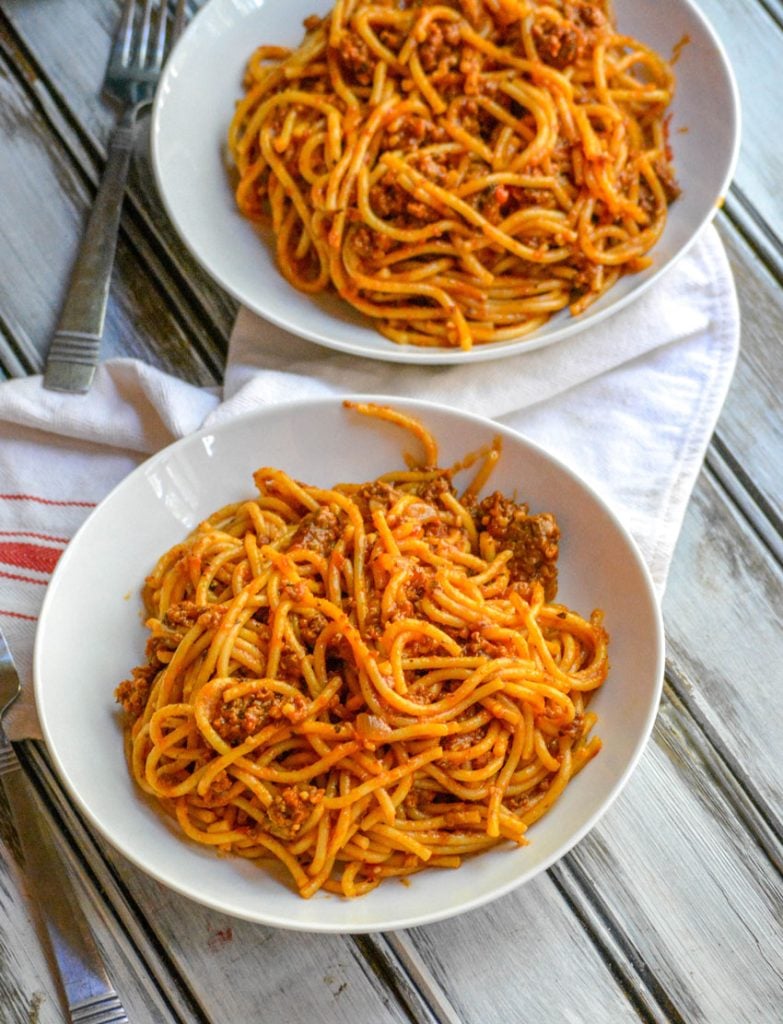 One Pot Spaghetti shown in two white serving bowls with forks and a cloth napkin in the background
