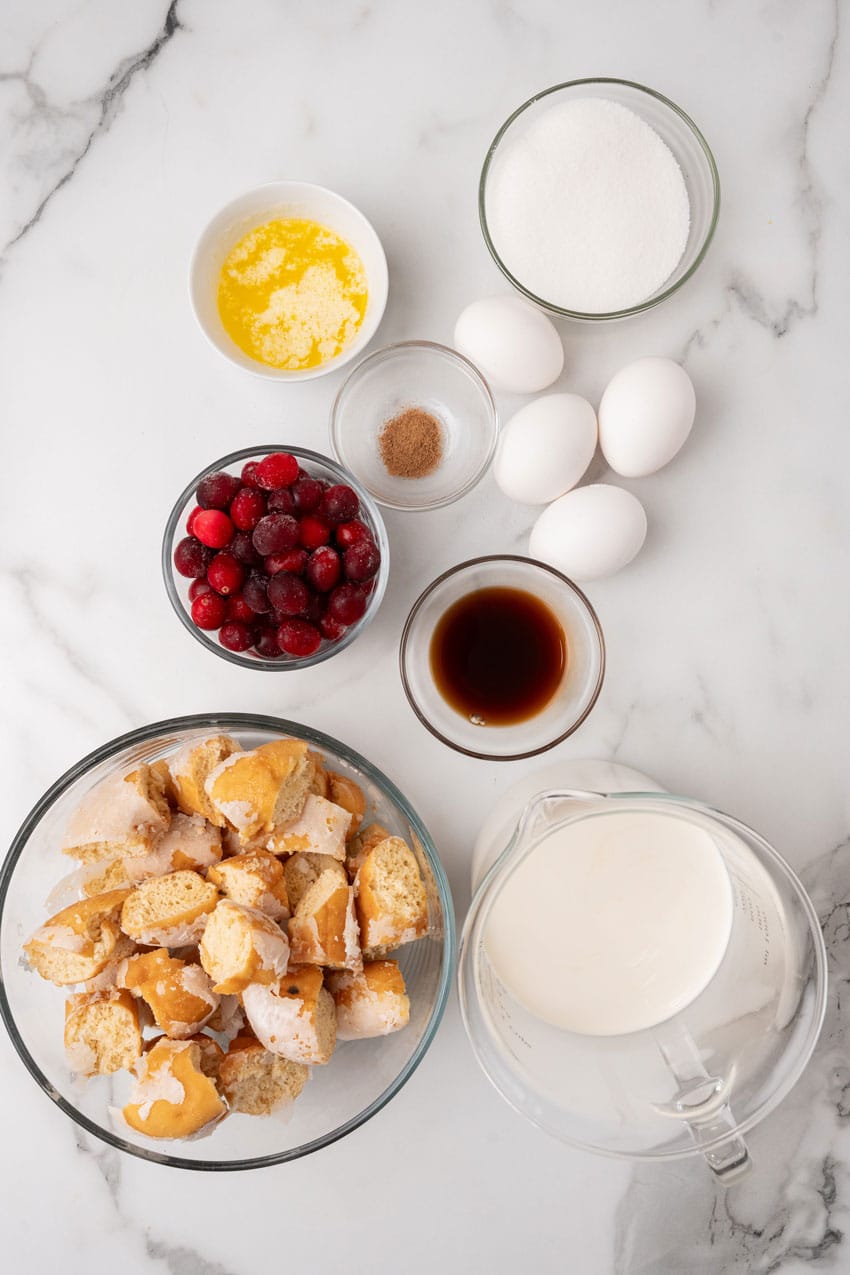 an overhead image showing the measured ingredients needed to make a batch of cranberry bread pudding with donuts