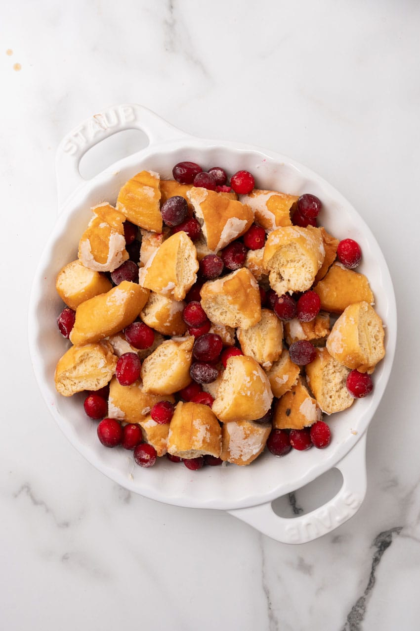 fresh cranberries and donut pieces in a white pie dish