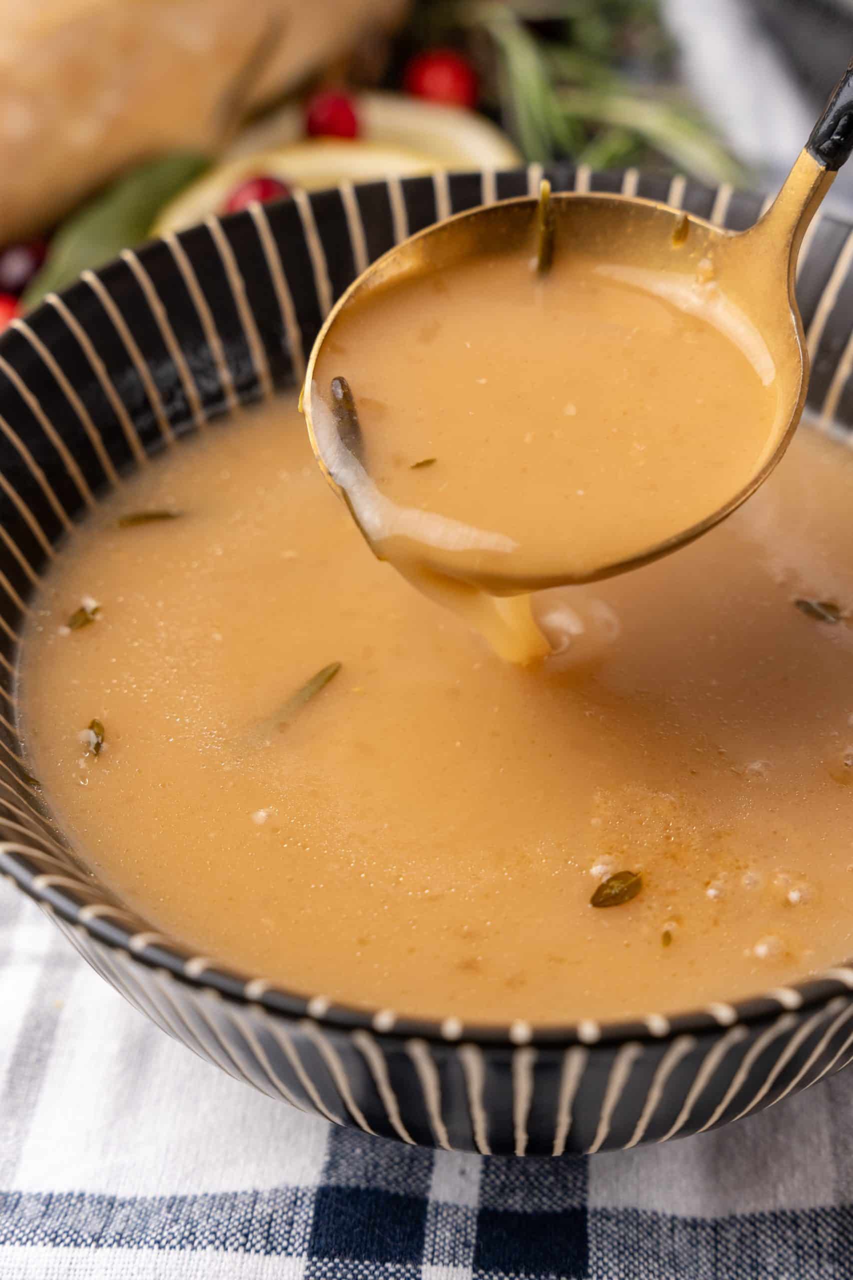 a golden ladle scooping instant pot turkey gravy out of a bowl