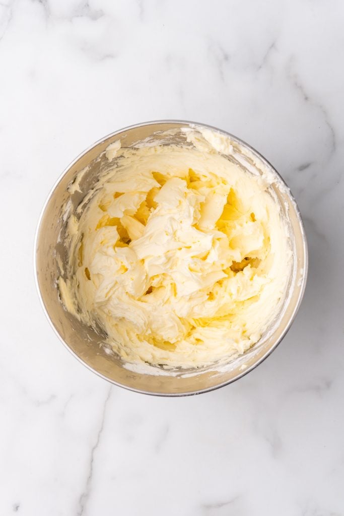 fluffy white buttercream frosting in a metal mixing bowl