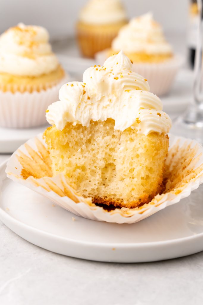 an unwrapped champagne cupcake with a bite taken out to reveal the fluffy center