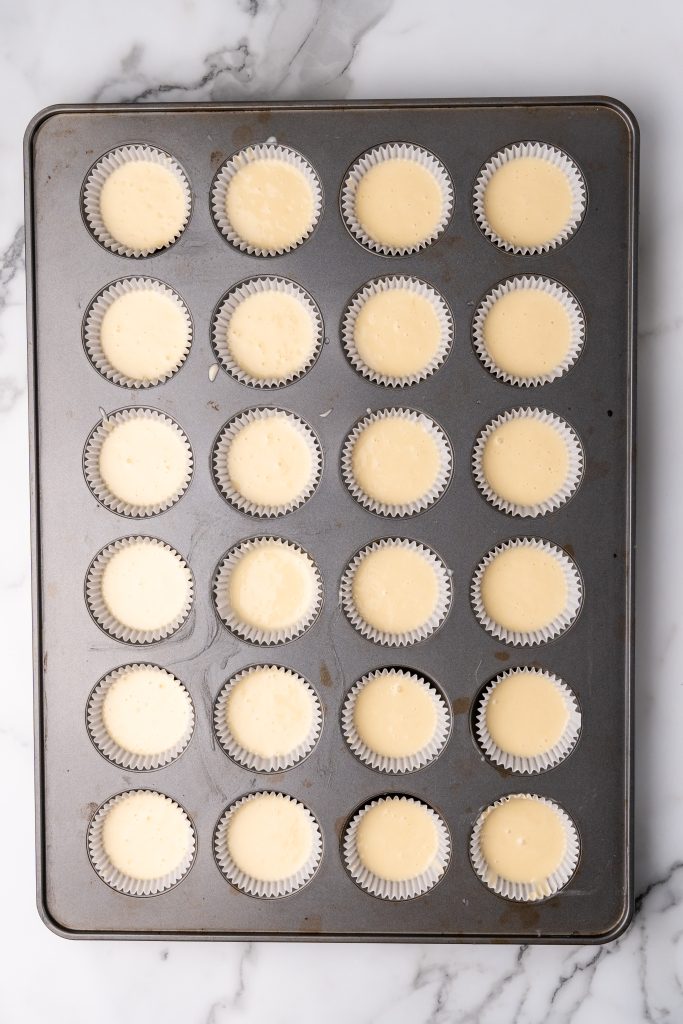 champagne cupcake batter in paper liners in a large muffin tin
