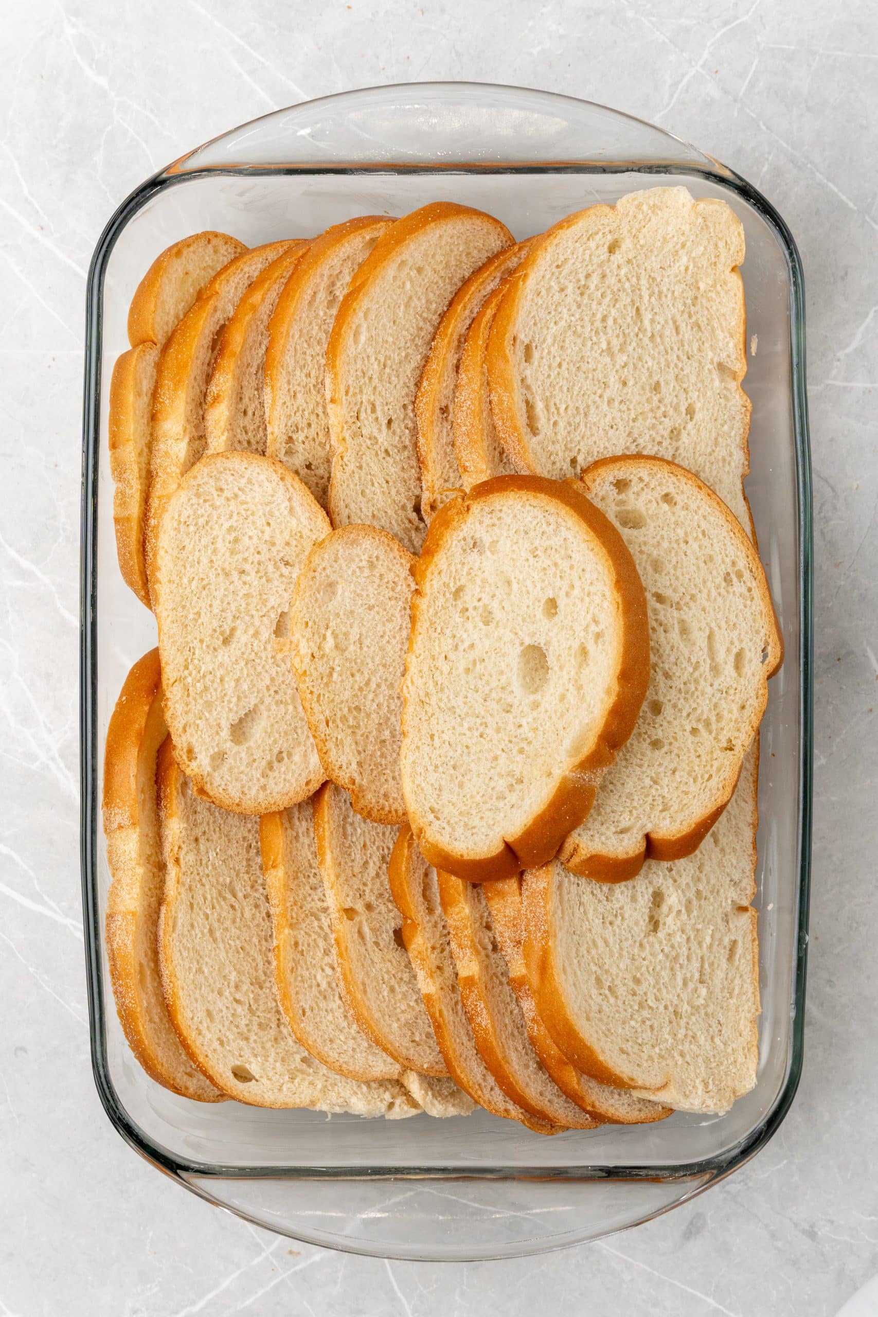 slices of bread arranged in a glass 9x13 inch baking dish