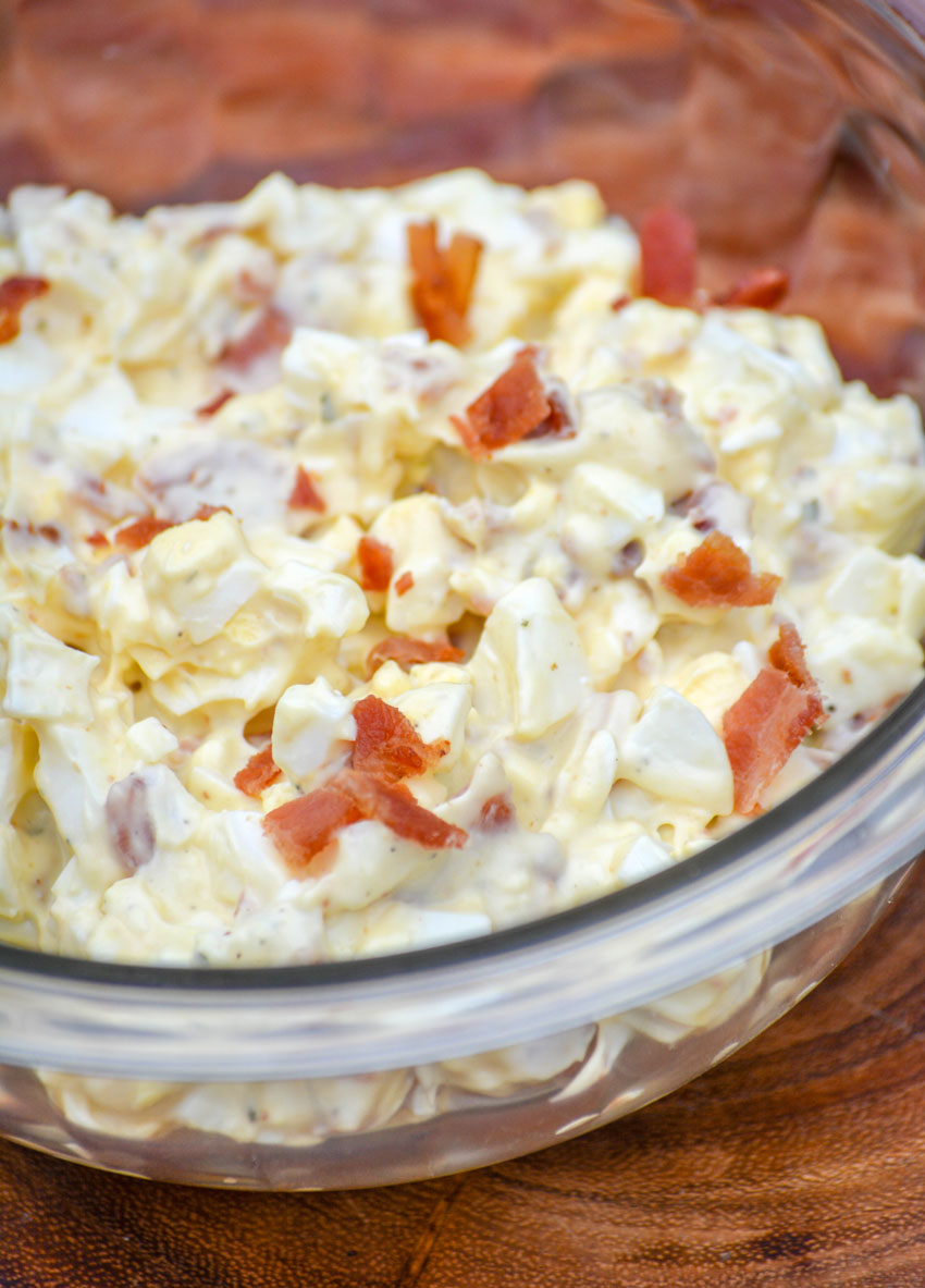 BACON RANCH EGG SALAD IN A SMALL GLASS BOWL ON A WOODEN CUTTING BOARD