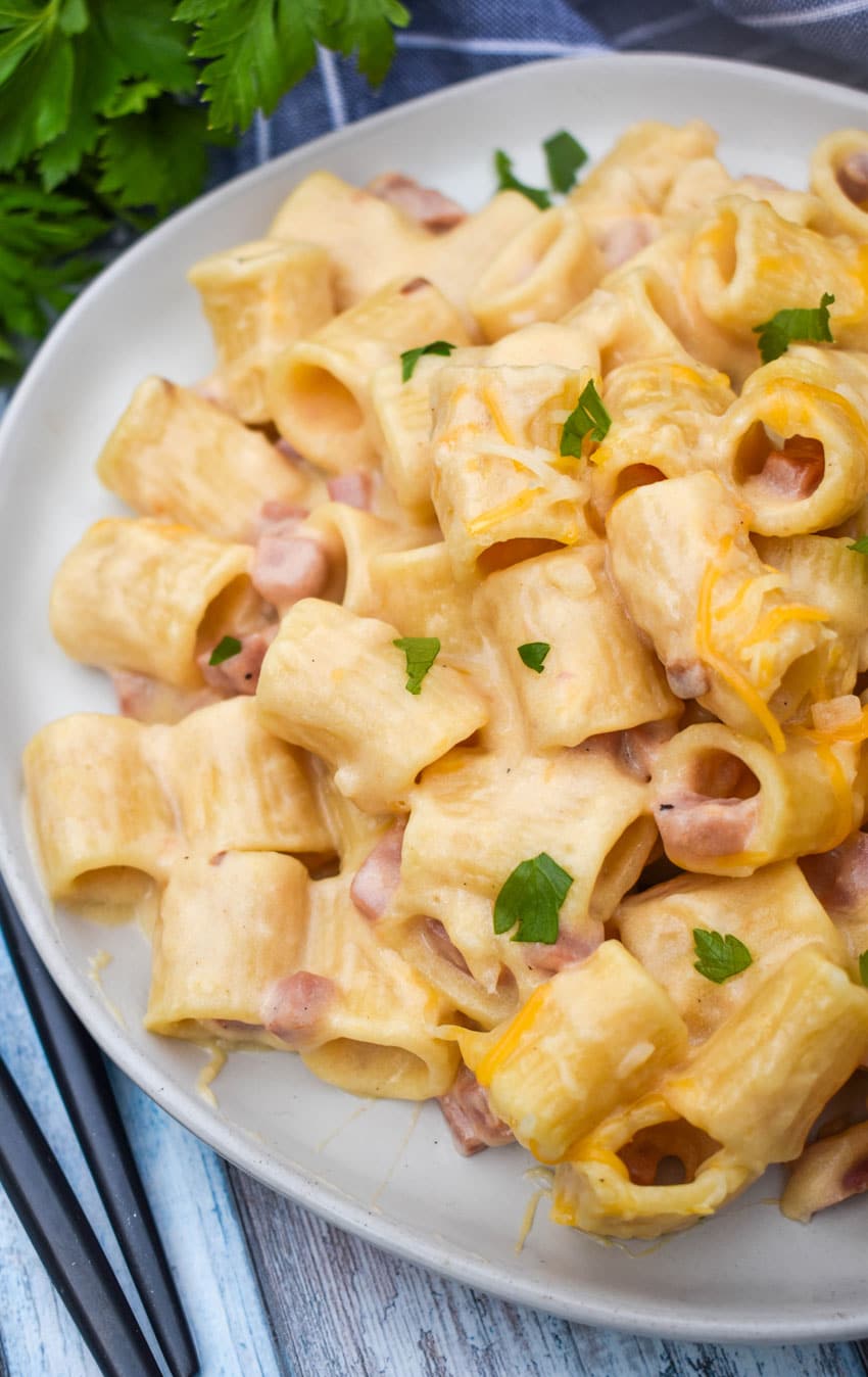 cheesy riggies pasta with ham on a white plate