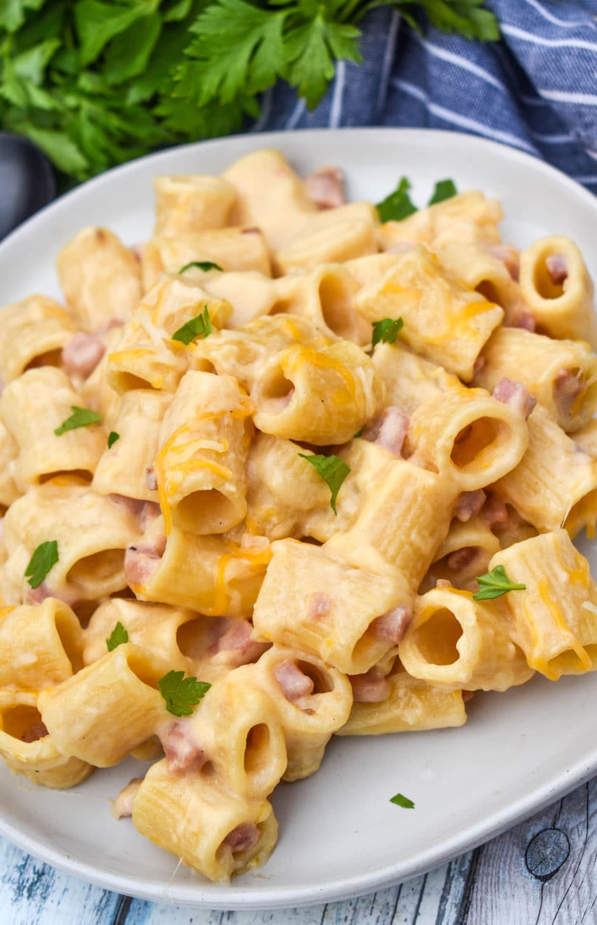 cheesy riggies pasta with ham on a white plate