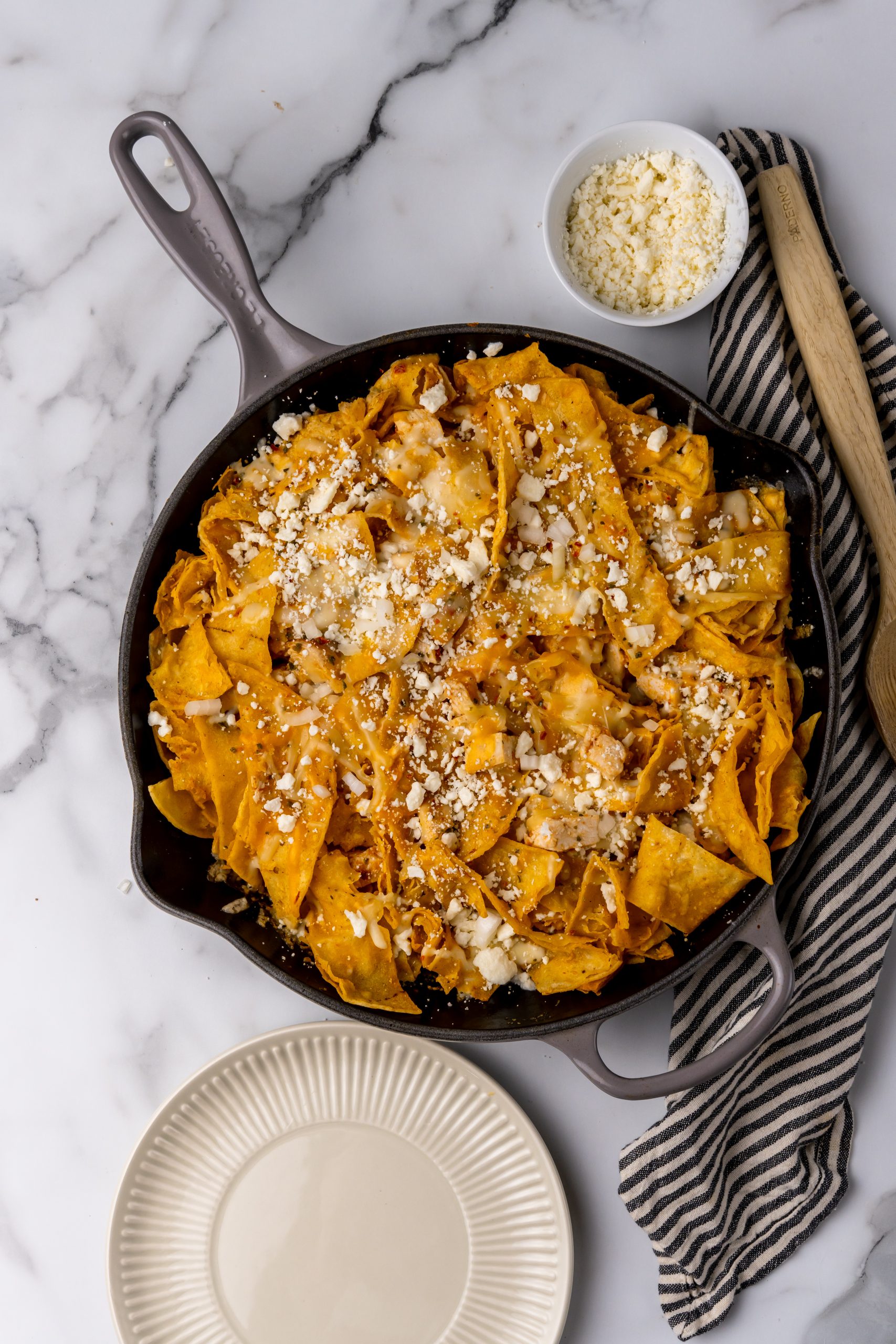 cheesy chicken chilaquiles skillet on a marble countertop