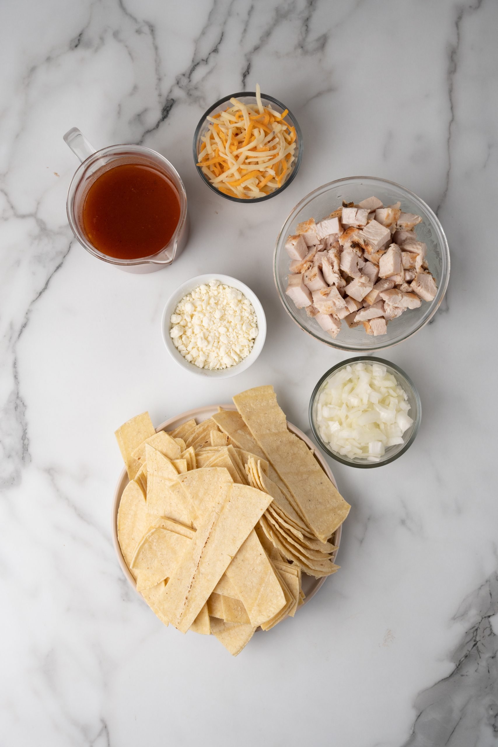 an overhead image showing the measured ingredients needed to make a batch of cheesy chicken chilaquiles