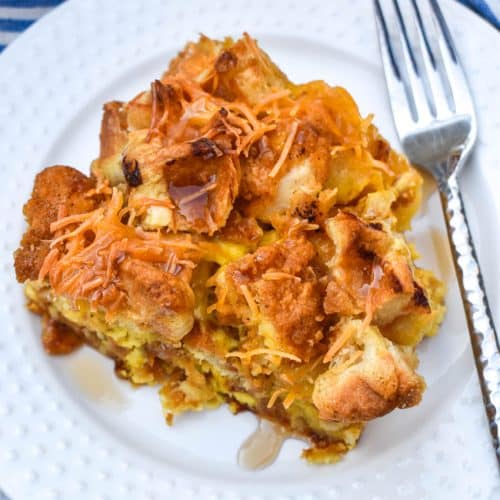 a slice of chicken and waffles casserole on a small white plate with a silver fork resting on the edge