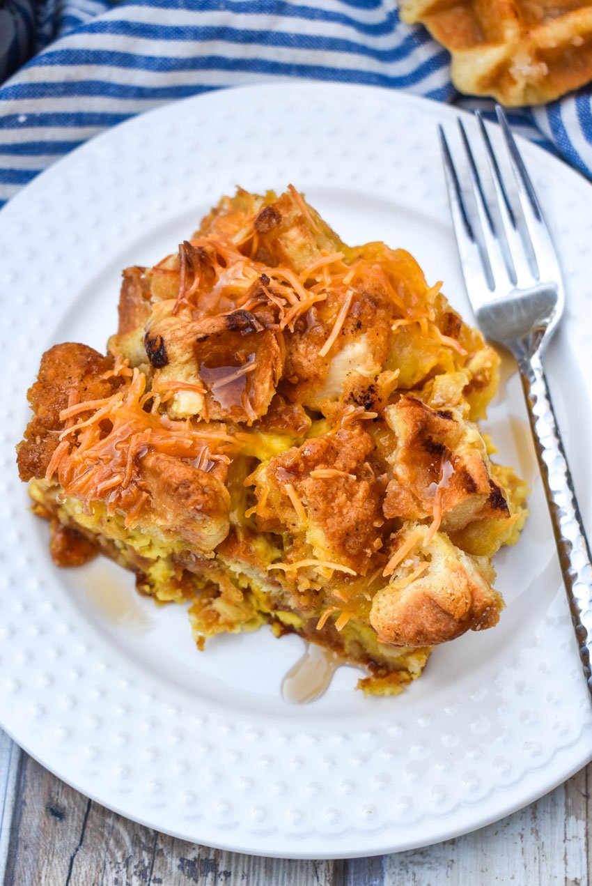 a slice of chicken and waffles casserole on a small white plate with a silver fork resting on the edge