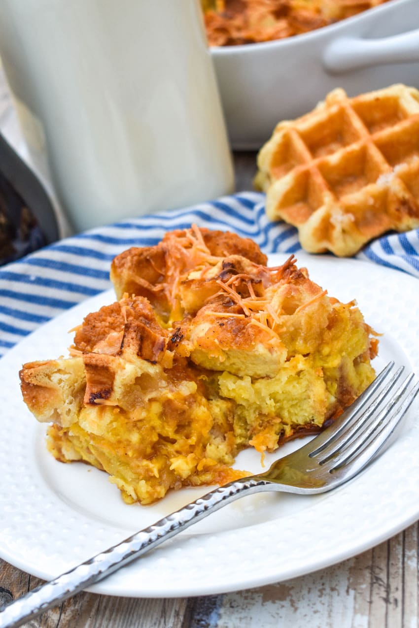 a slice of chicken and waffles casserole on a small white plate with a silver fork resting on the edge