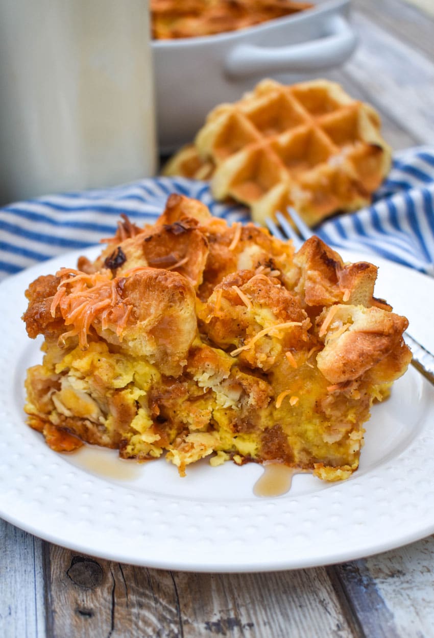a slice of chicken and waffles casserole on a small white plate with a silver fork resting on the edge