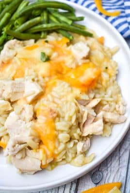 cheesy chicken rice pilaf casserole on a white plate with green beans on the side