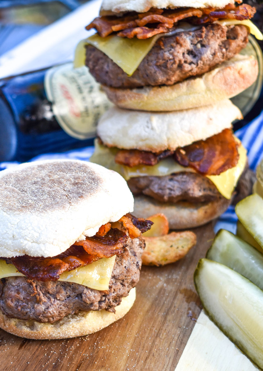 cheesy guinness burgers on english muffins on a wooden cutting board