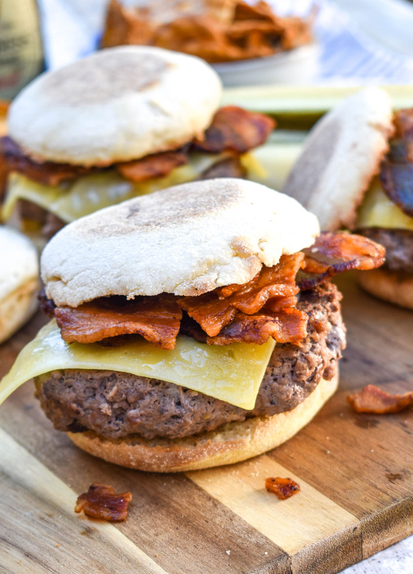 guinness burgers with bacon and irish cheddar on a wooden cutting board