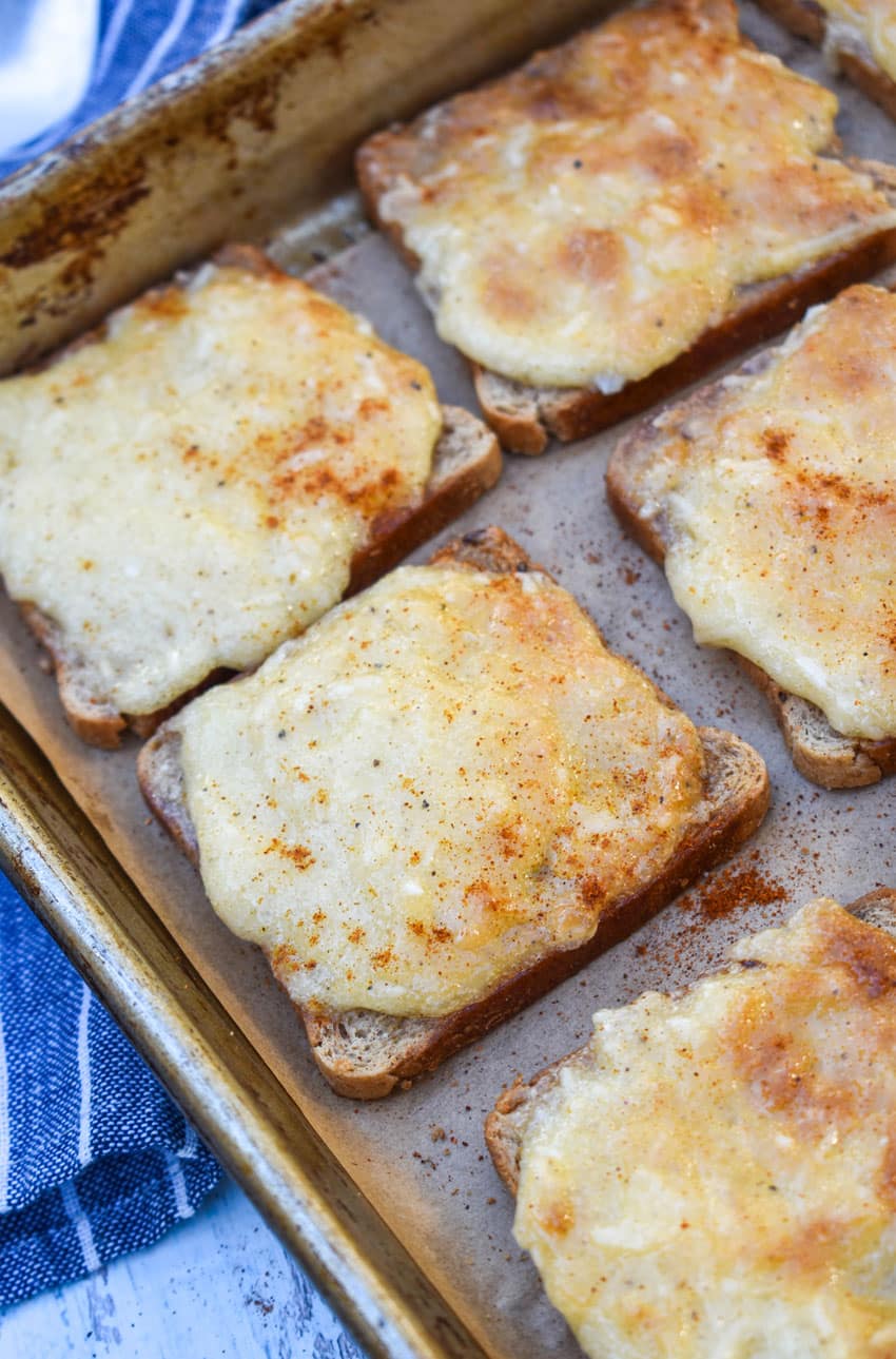 cheesy parmesan rye cocktail bites arranged in rows on a metal baking sheet