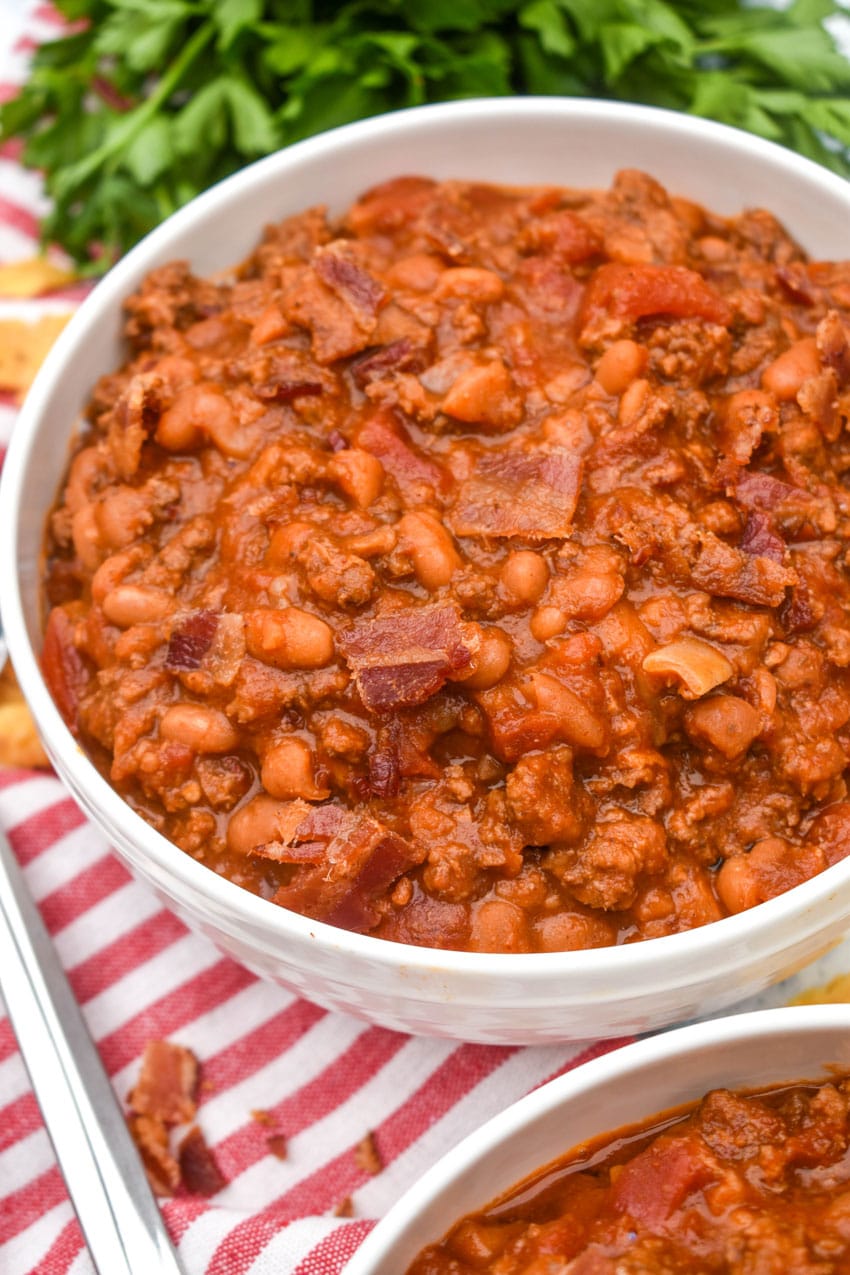 ground beef baked bean chili in a white bowl surrounded by corn chips