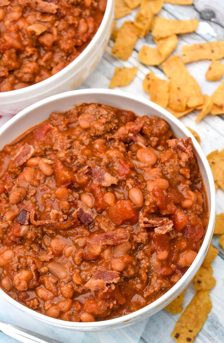 ground beef baked bean chili in a white bowl surrounded by corn chips
