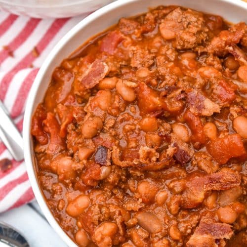 ground beef baked bean chili in a white bowl surrounded by corn chips
