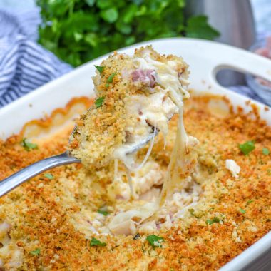 a silver spoon holding up a scoop of cheesy chicken cordon bleu casserole