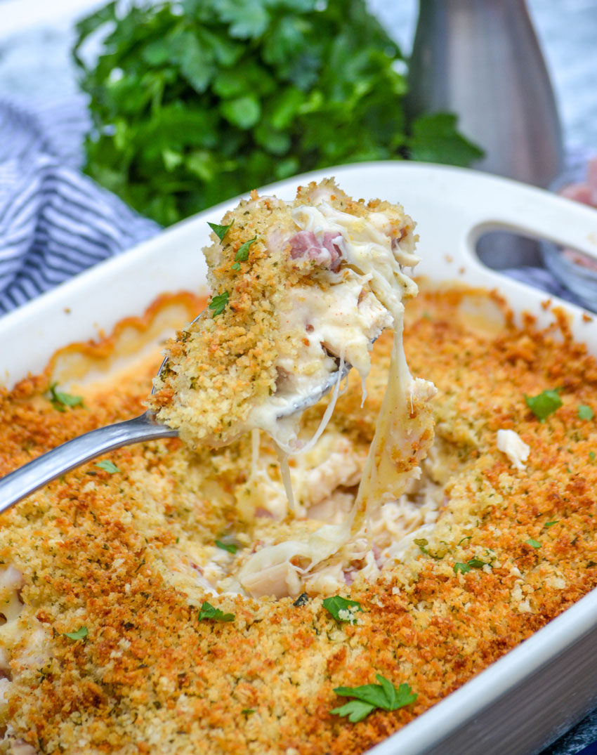 a silver spoon holding up a scoop of cheesy chicken cordon bleu casserole