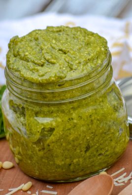 NONNA'S HOMEMADE BASIL PESTO IN A GLASS JAR ON A WOODEN CUTTING BOARD