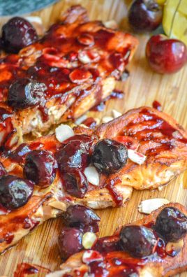 PIECES OF PAN SEARED SALMON TOPPED WITH FRESH CHERRY ALMOND SAUCE ON A WOODEN CUTTING BOARD