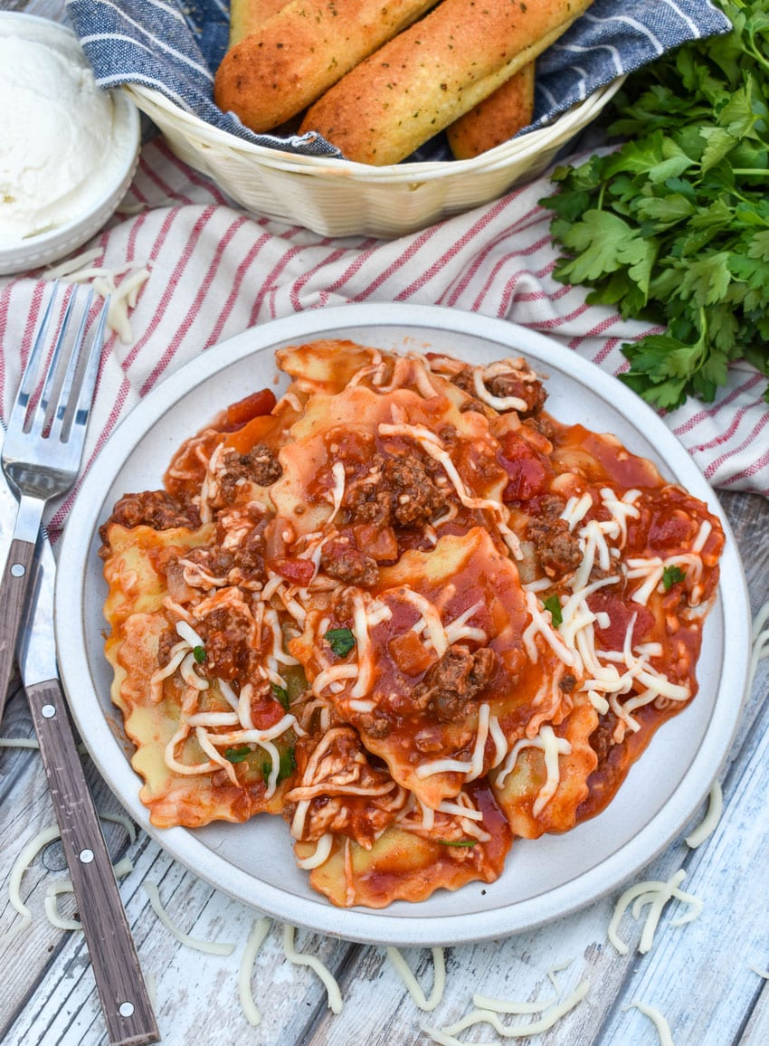 RAVIOLI SKILLET LASAGNA ON A WHITE PLATE WITH A FORK RESTING ON THE SIDE
