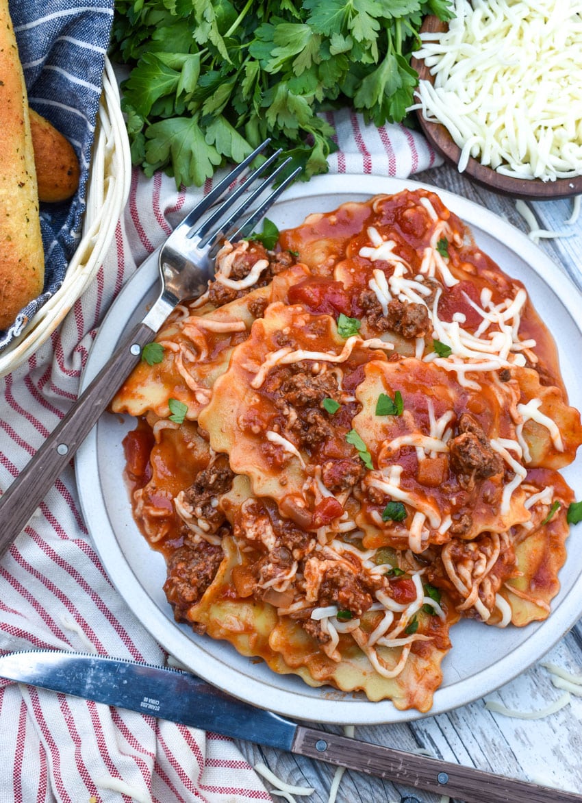RAVIOLI SKILLET LASAGNA ON A WHITE PLATE WITH A FORK RESTING ON THE SIDE