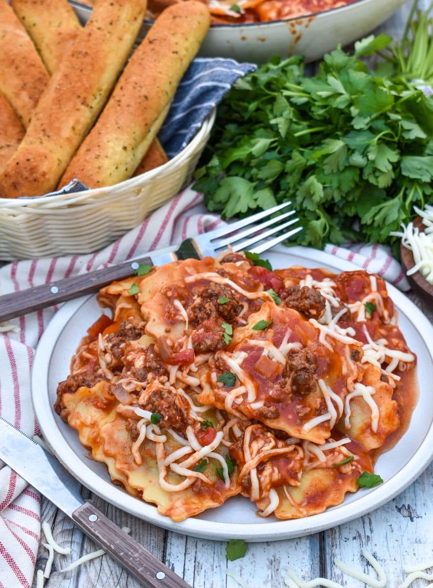 RAVIOLI SKILLET LASAGNA ON A WHITE PLATE WITH A FORK RESTING ON THE SIDE