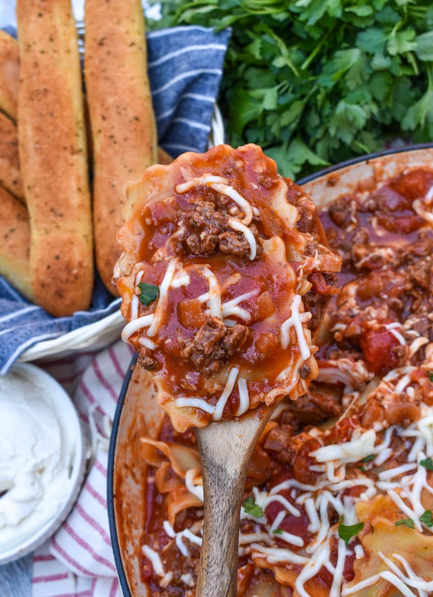 A WOODEN SPATULA HOLDING UP A SCOOP OF RAVIOLI SKILLET LASAGNA