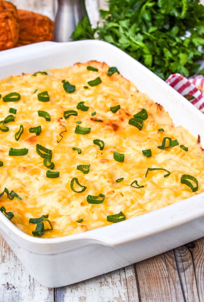 three cheese chicken and rotini pasta casserole in a white casserole dish garnished with sliced green onions
