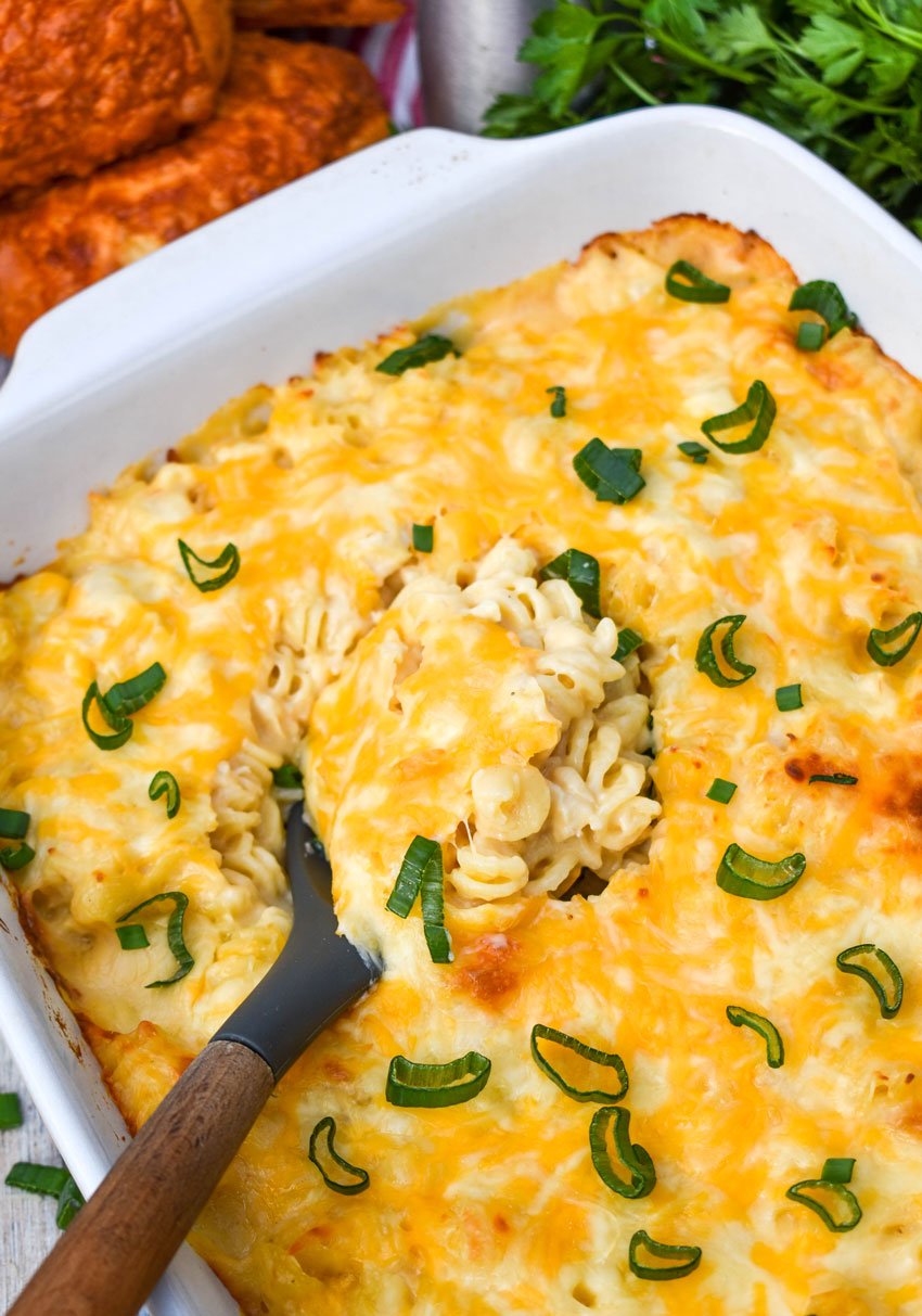 a black spoon in a cheesy chicken mac and cheese casserole