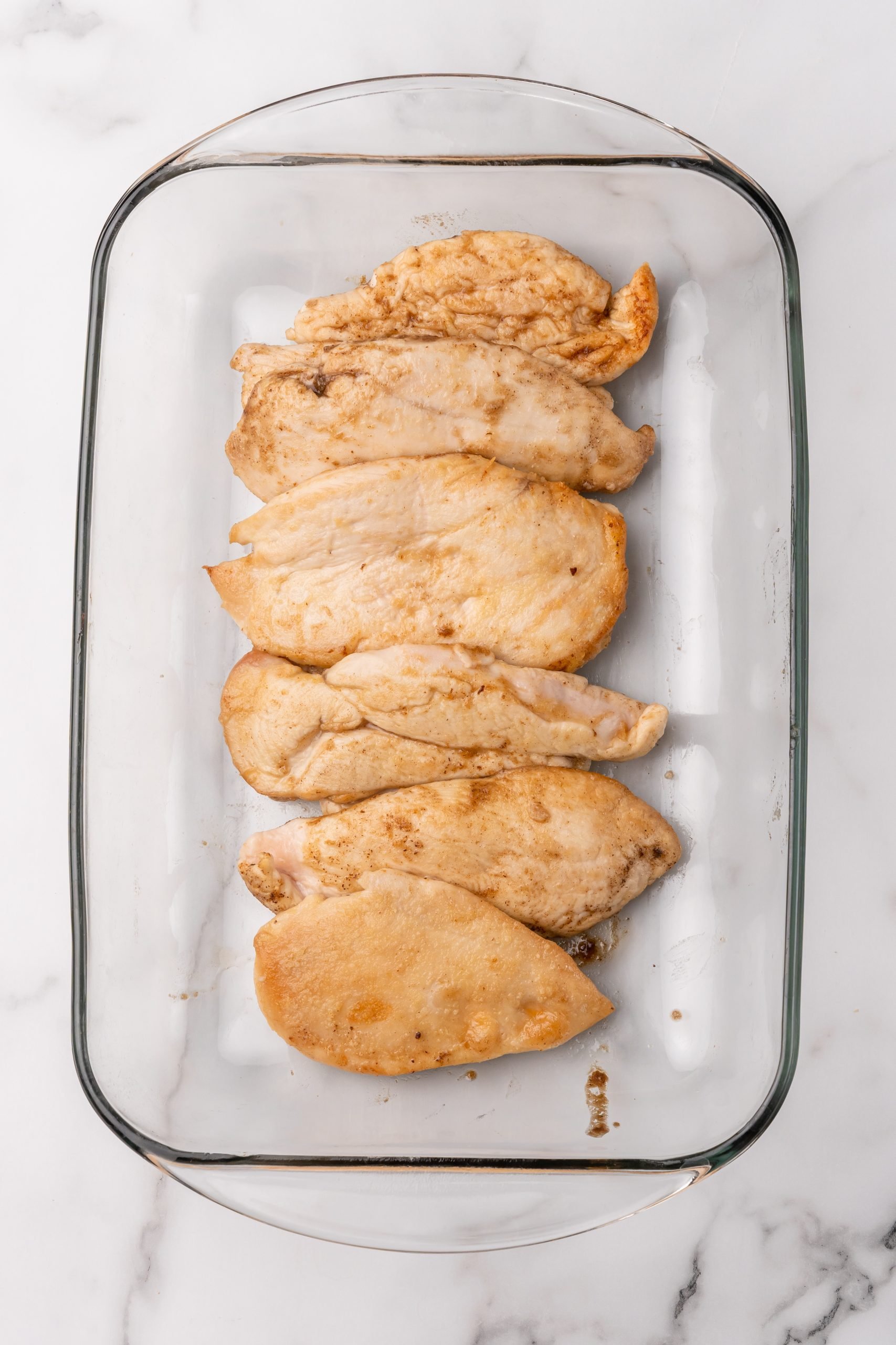 pan fried chicken breasts arranged in a glass baking dish
