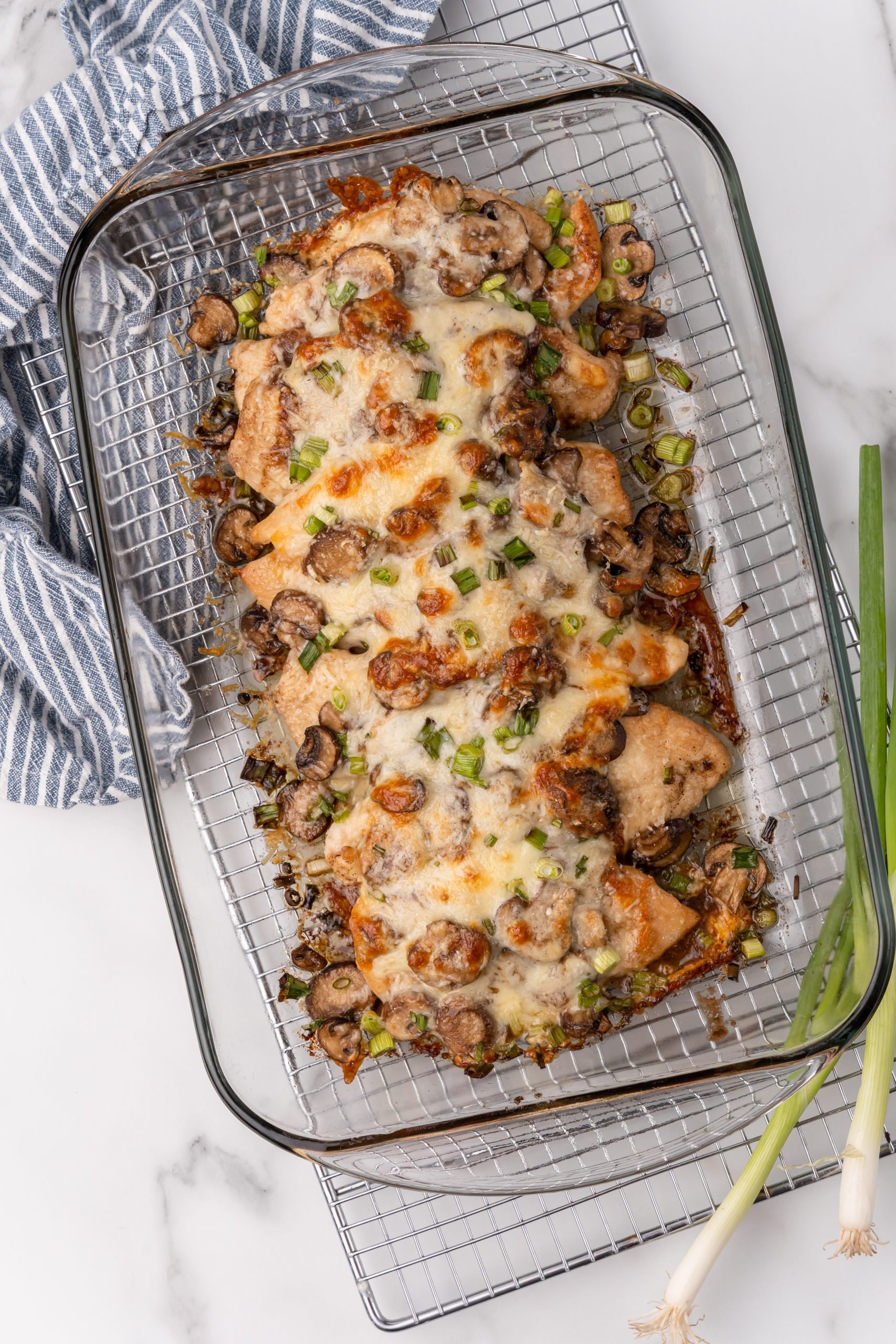 cheese covered baked chicken lombardy in a glass baking dish