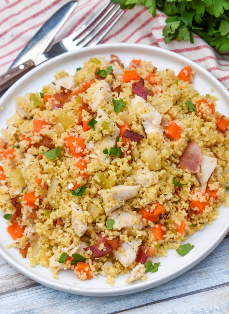one pot chicken bacon couscous topped with fresh herbs on a white plate