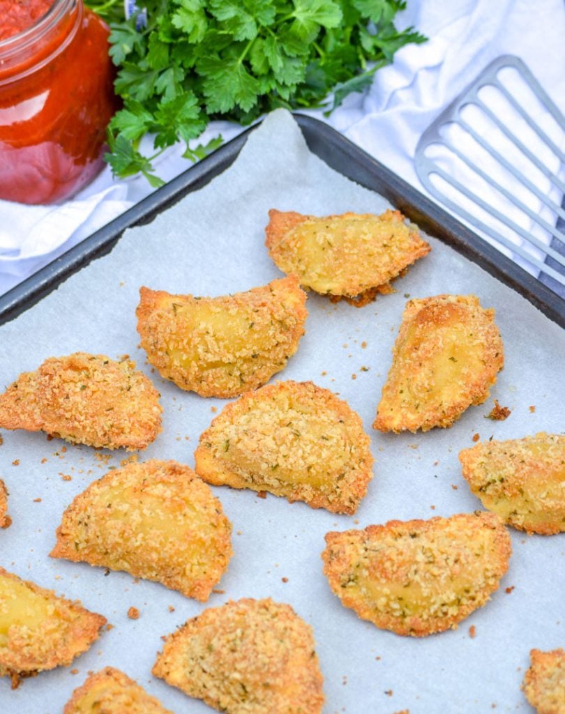 Oven Baked Toasted Ravioli shown on a parchment covered baking sheet