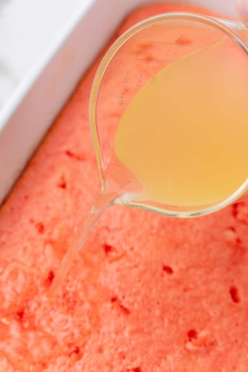 margarita mixer being poured over a strawberry poke cake