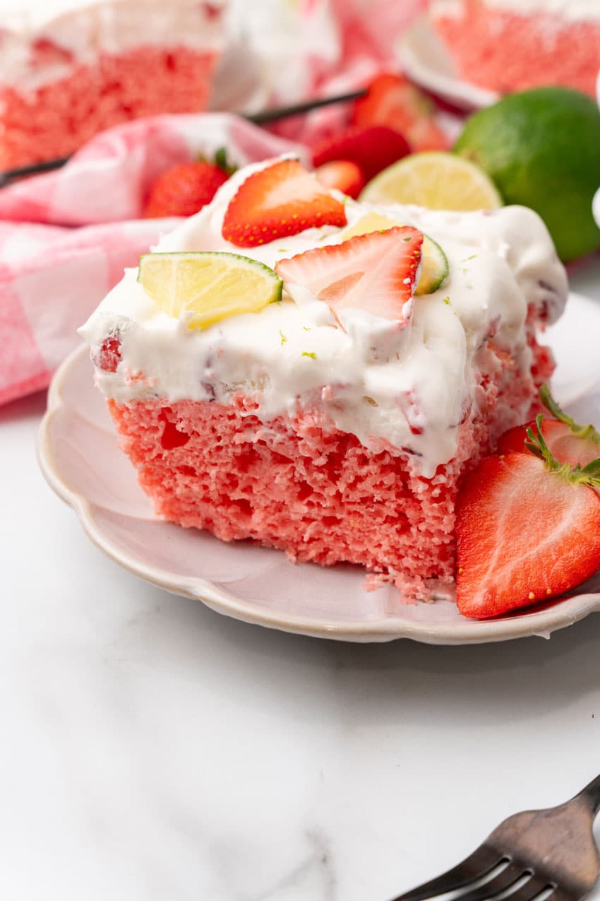 slices of strawberry margarita poke cake on small white dessert plates