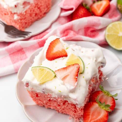 slices of strawberry margarita poke cake on small white dessert plates