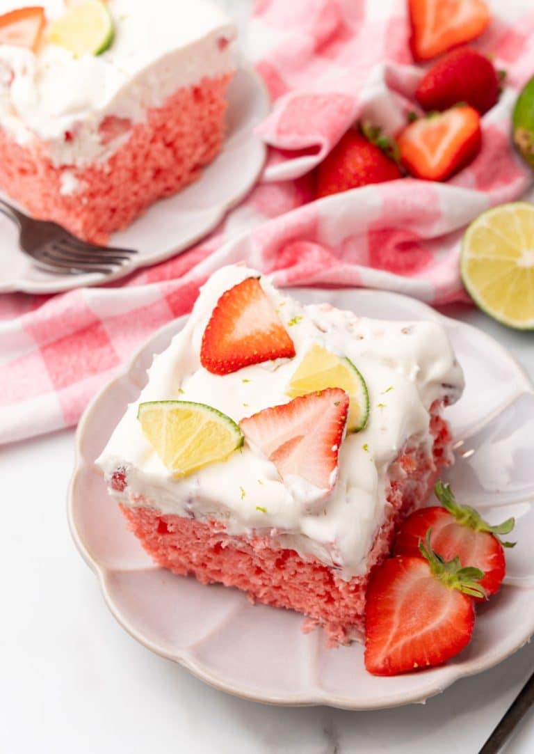 slices of strawberry margarita poke cake on small white dessert plates